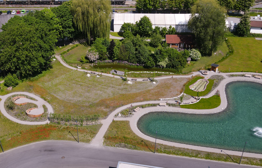 Übersicht über den gesamten Naturerholungspark inmitten eines Gewerbegebietes kurz nach der Anlage (Frühjahr 2023). © Maria Siegl
Wesentliche Elemente:
    • großzügige Sitzrondelle inmitten eines Prachtstaudenbeetes 
    • Weidentunnel mit Bänken als schattiger Rastplatz und Verbindungselement
    • Kräuter- und Duftstaudenbeete an den Böschungen des Löschwasserteiches
    • Kneippbecken mit umgebender Wiese
    • zentrale Blumenwiese mit Sitzbänken
    • Sumpfgraben mit Beobachtungsplattform
    • Sportwiese mit umgebender Vogelschutzhecke
    • artenreiche Sickermulden entlang der Straße
